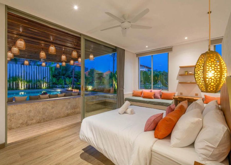 Bedroom at nighttime with view of garden and swimming pool